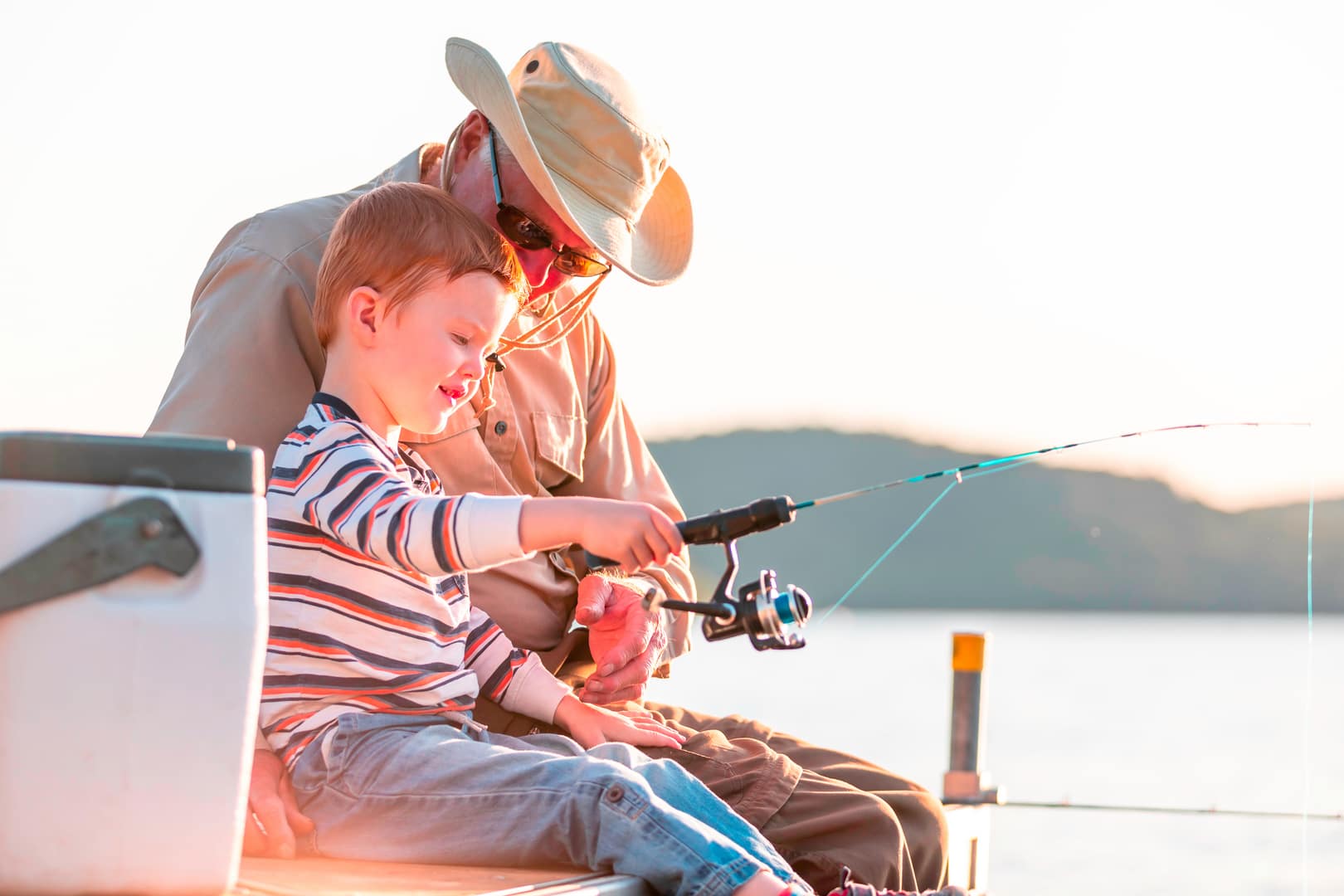 A grandfather teaches his grandson to fish.