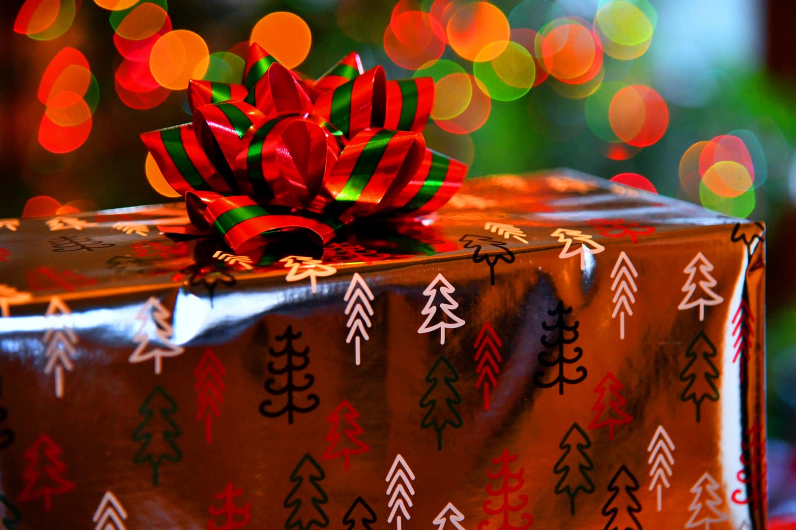 A wrapped present sits near a Christmas tree.